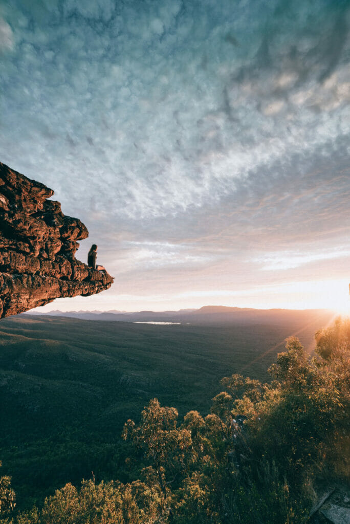 man sitting on edge of rock
